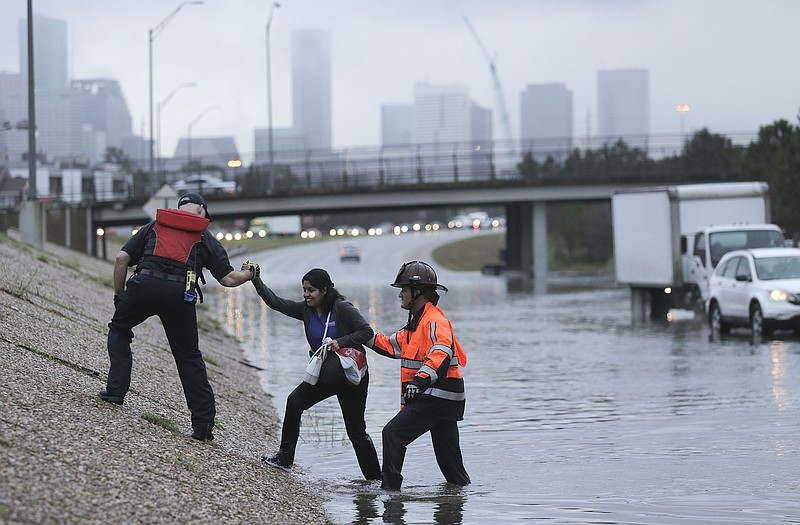 A woman is helped out of a flooded 288 on Wednesday, Jan. 18, 2017, in Houston. Flash flood warnings are in effect for the Houston region, where torrential rains prompted officials to close some schools and delay opening many others on Wednesday. Public transportation has been delayed or suspended in the area. 