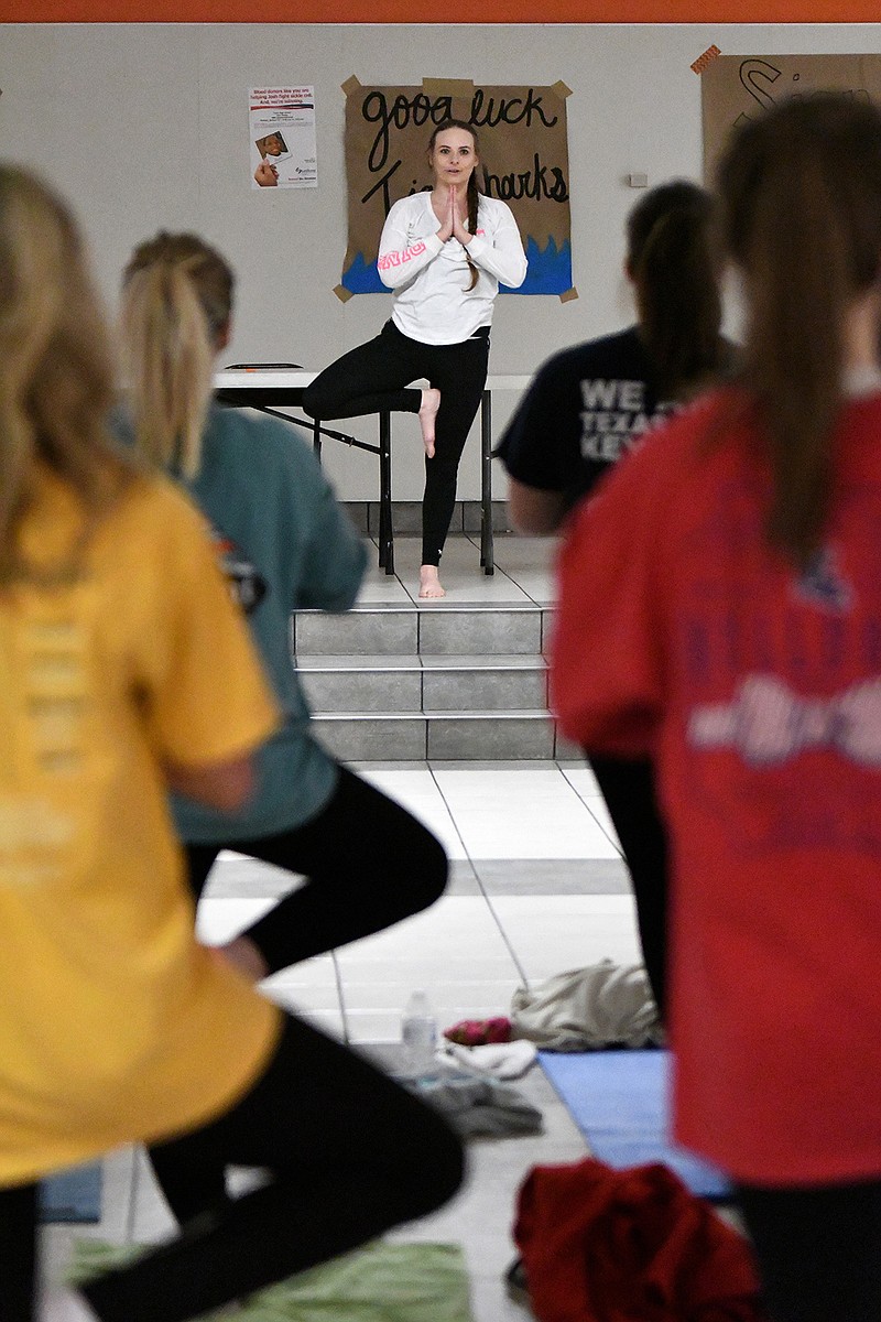 Yoga instructor Rachel Burnett leads the Texas High School Rosebuds through the tree pose Thursday during their monthly club meeting at the Dan Haskins Student Center. The Rosebuds are a community service and leadership club at Texas High who helps children in need and volunteer in the community.