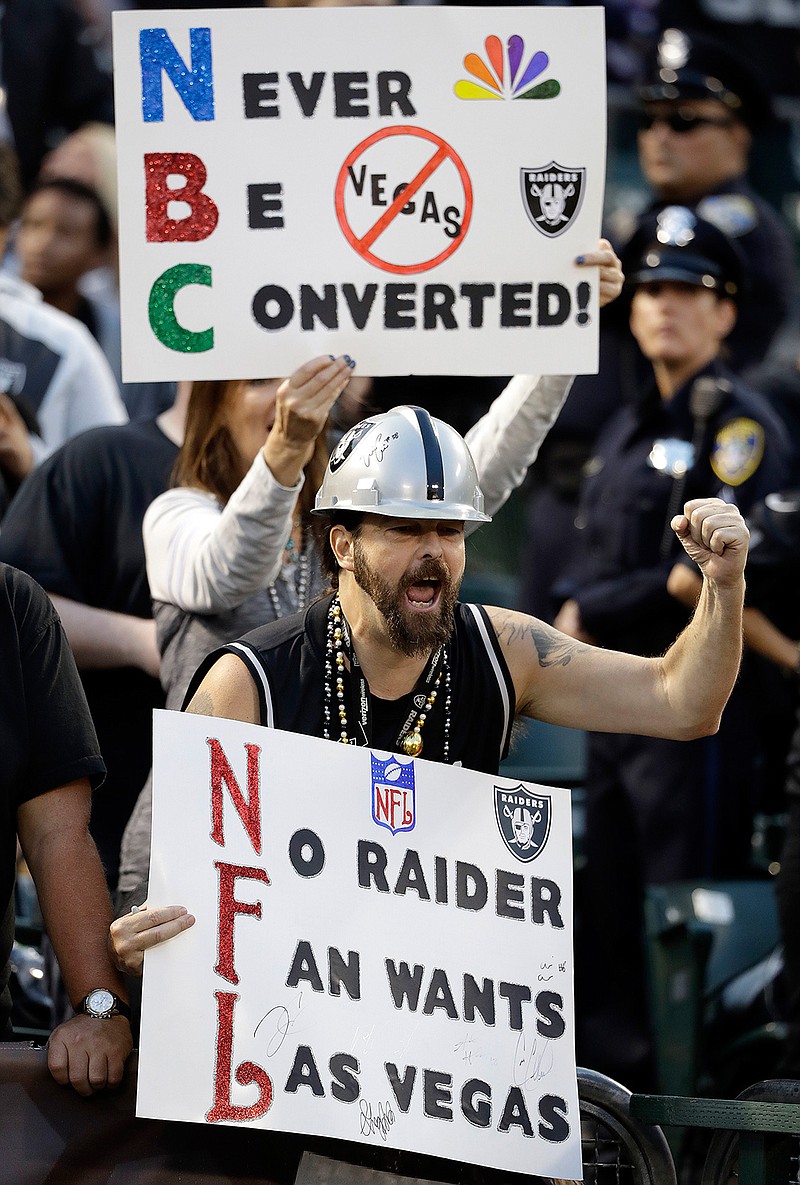 In this Nov. 6, 2016, file photo, Oakland Raiders fans hold up signs about the team's possible move to Las Vegas during an NFL football game between the Raiders and Denver Broncos in Oakland, Calif. The Oakland Raiders have filed paperwork to move to Las Vegas. Clark County Commission Chairman Steve Sisolak told The Associated Press on Thursday, Jan. 19, 2017, that he spoke with the Raiders.