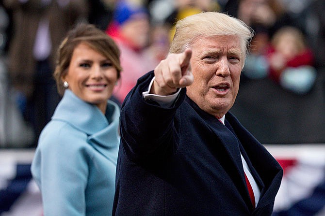 President Donald Trump, accompanied by first lady Melania Trump, points to members of the crowd Friday as they walk in his inaugural parade on Pennsylvania Avenue outside the White House in Washington.