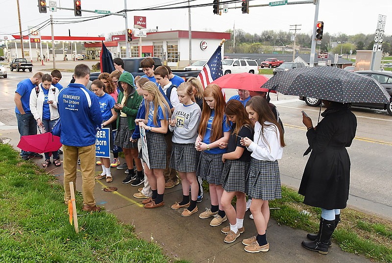 Pat Castle, back to camera, leads the Life Runners group in prayer in April 2016 at the intersection of Stadium Boulevard and Jefferson Street in Jefferson City. The largest student chapter of the worldwide organization is from Helias High School and boasts 80 active members.