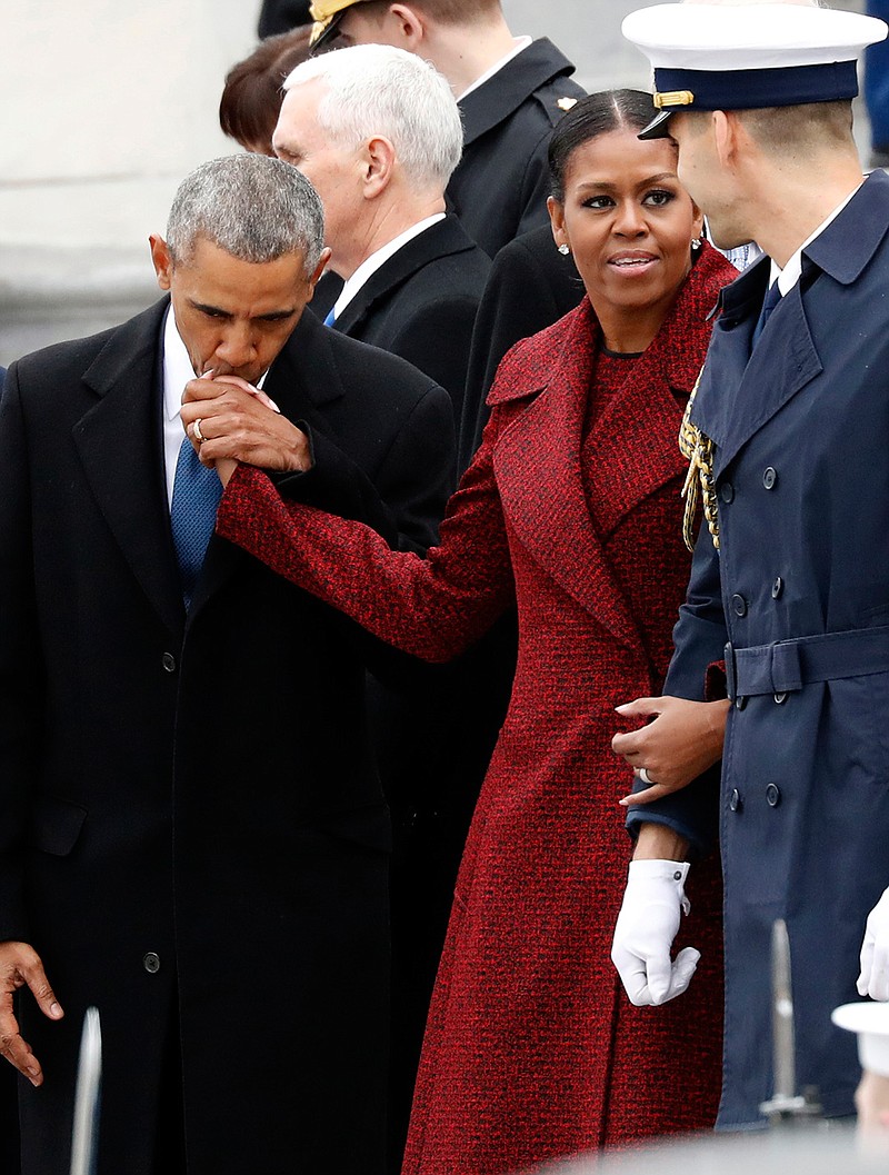 Former President Barack Obama kisses the hand of his wife Michelle Obama, during a departure ceremony on the East Front of the U.S. Capitol, Friday, Jan. 20, 2017 in Washington. 