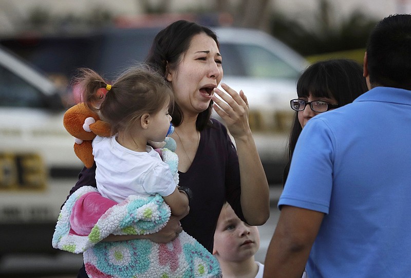 woman holds her child after San Antonio police helped her and other shoppers exit the Rolling Oaks Mall on Sunday in San Antonio, after a deadly shooting. Authorities say several were injured after a robbery at the shopping mall. 
