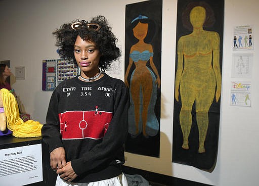 In this Friday, Dec. 9, 2016, photo, Ajani Russell poses with her artwork "Female Figures" prior to the Animated Women symposium at California Institute of the Arts, in Valencia, Calif. 