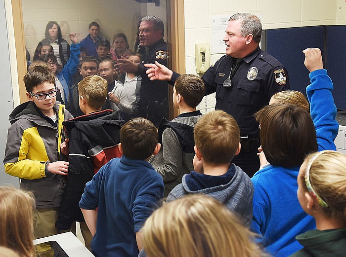 Officer Les Martin explains the use of the two-way mirror in the police station to St. Joseph Cathedral School fourth grade students. 