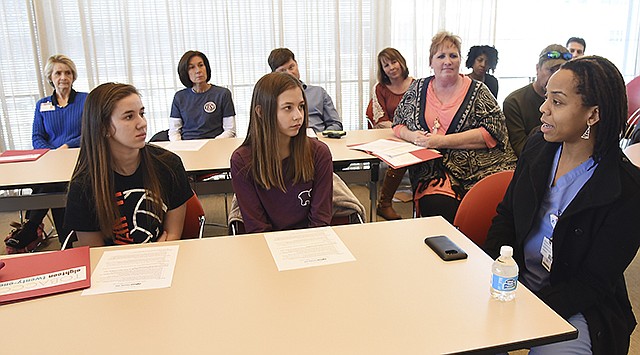 Madison Irvin, foreground left, and classmate Paige Henry listen Thursday as Dr. Allyson Walker, right, speaks at the Tobacco 21 town hall about her first-hand knowledge of the dangers of cigarette smoking. Walker is a cardiothoracic surgeon at St. Mary's Hospital and has seen person after person with damage due to smoking. Irvin and Henry are freshman at Blair Oaks High School and active in the Council for Drug Free Youth's UPLIFT program. Tobacco 21 hosted the informative meeting where several speakers went into detail about their desire to make the legal cigarette purchase age 21.