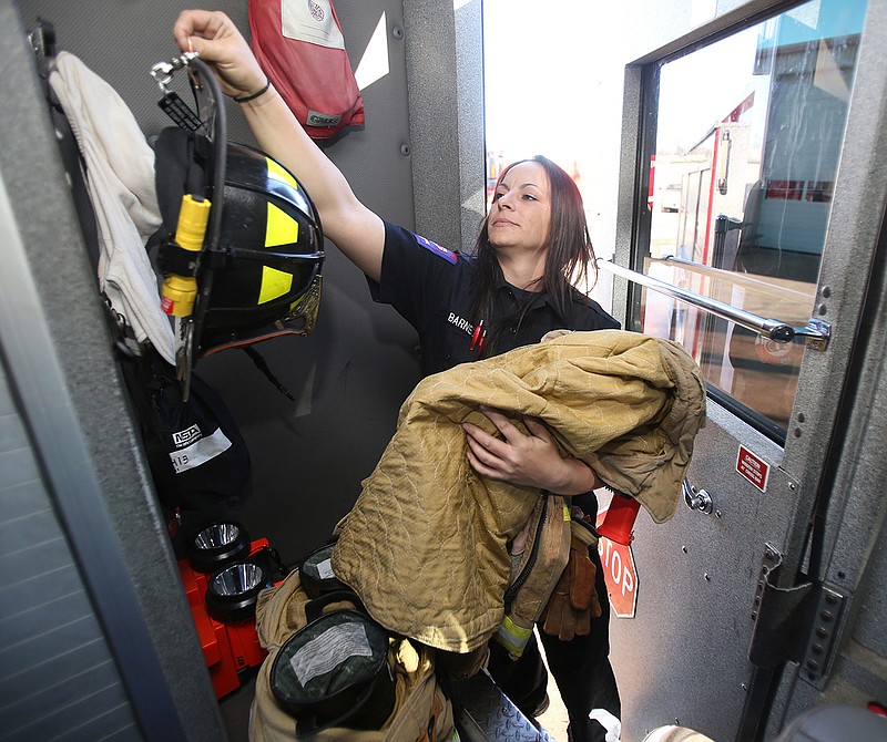 In a Monday, Jan. 30, 2017 photo, Amber Barnes reaches for her helmet during a shift at her fire station, in Bellmead, Texas. Amber Barnes still gets surprised looks when she arrives at the scene of a local emergency after becoming the first female firefighter for the city last summer.