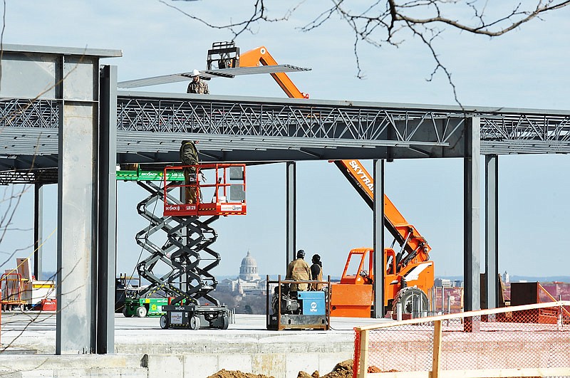 Coil Construction of Columbia is the contractor on the new Goodwill store job in Jefferson City on South Ten Mile Drive, next to Arby's. While welders on lifts do their work, another crew hoists roofing material to the top to be able to start fastening it to roof beams.