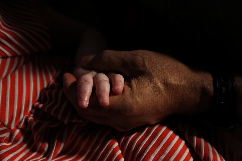 Mohamed Bzeek holds the hand of his 6-year-old foster daughter, who was born with a rare brain malformation and cannot see, hear or speak. He has cared for terminally ill foster children in Los Angeles County for more than two decades. 