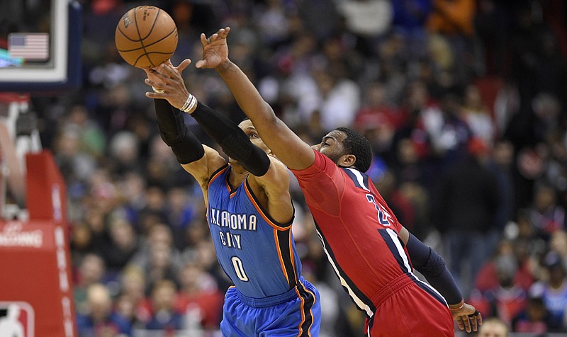 Oklahoma City Thunder guard Russell Westbrook, left, and Washington Wizards guard John Wall reach for the ball Monday during the second half in Washington.