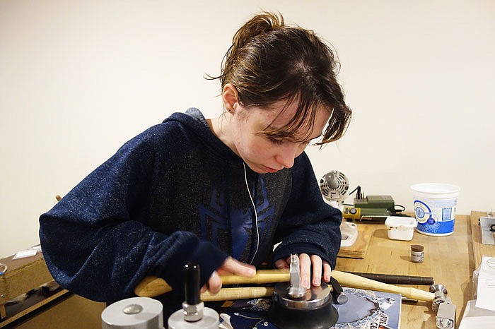 Lily Mullen, part of the design team at Creating Unkamen, begins crafting what will be a horseshoe-shaped charm. She commutes over an hour to work in Fulton, but for her it's worth it.