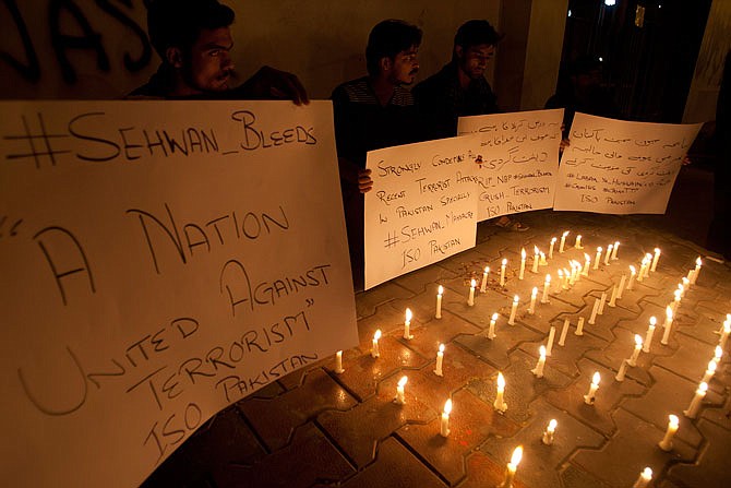 Pakistani students light candles to condemn the attack on a shrine in interior Sind province Thursday in Karachi, Pakistan. An Islamic State suicide bomber targeted worshippers at a famous shrine in southern Pakistan killing 75 people.