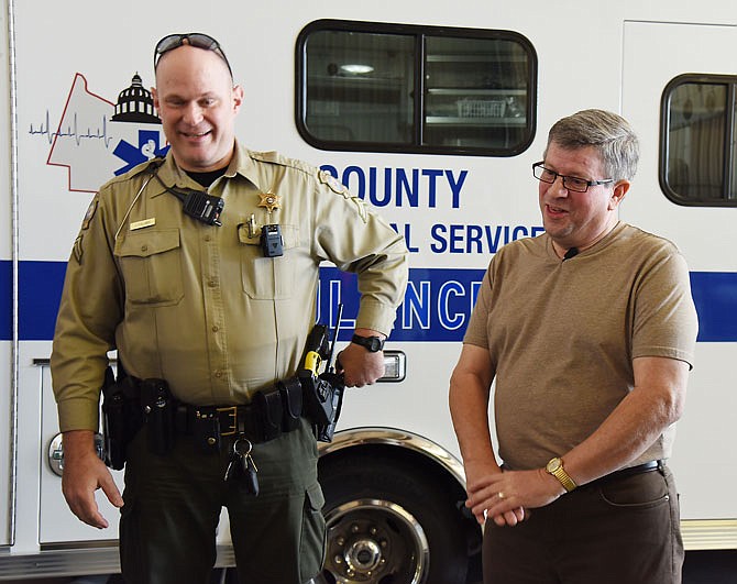 Roger Baston, right, mimics the hand-over-hand motion used in CPR during a visit to emergency personnel who worked to save his life Nov. 29. He and his wife, Bev Baston, stopped in at the office of Cole County EMS to thank them in person for their cooperative effort to save him. At left is Cpl. John Fullmer of the Cole County Sheriff's Department who, along with others, responded when Baston was in cardiac arrest. 
