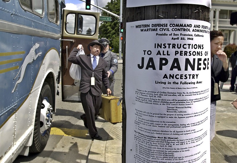 In this April 27, 2002 file photo, a copy of a poster from 1942 is posted in front of an antique Greyhound bus in downtown Watsonville, Calif., as participants reenact what happened to their relatives exactly 60 years earlier during their internment in 1942. Roughly 120,000 Japanese immigrants and Japanese-Americans were sent to desolate camps that dotted the West because the government claimed they might plot against the U.S.