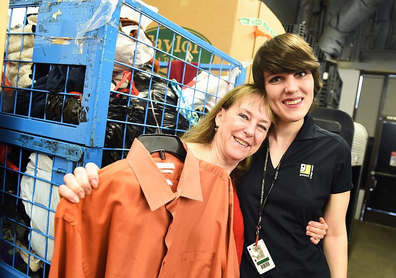 Linda Hoffman of Placentia, left, and Goodwill processing associate Caitlin Mulvihill, right, hold up a dress shirt that Hoffman's husband accidentally donated to Goodwill with $8,000 in the pocket. Hoffman's husband was secretly saving money in hopes of taking her on a surprise trip to Italy.