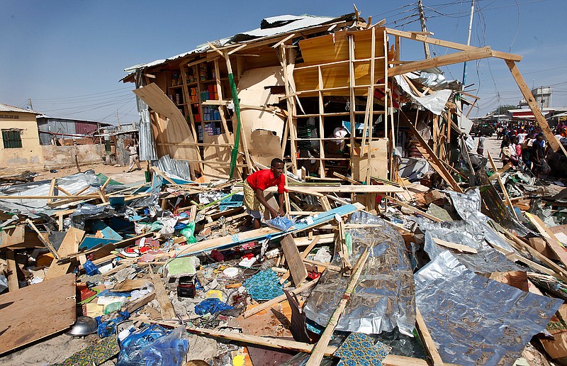 A shopkeeper surveys the wreckage of shops destroyed by a blast in a market in the capital Mogadishu, Somalia Sunday, Feb. 19, 2017. A Somali police officer says a blast at a busy market in the western part of Somalia's capital tore through shops and food stands and killed more than a dozen people and wounded many others. 