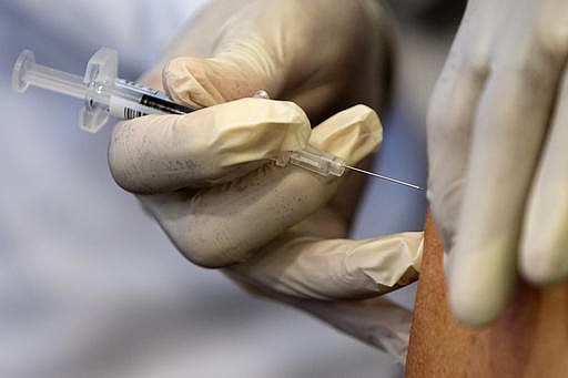 In this Thursday, Sept. 17, 2015 file photo, a nurse gives administers a flu vaccine shot in Washington. 