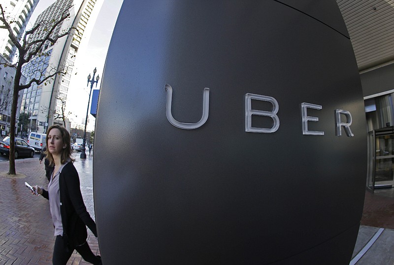 A woman walks past the company logo of the internet car service, Uber, on Dec. 16, 2014, in San Francisco.