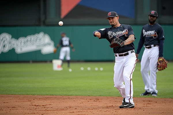 Braves infielder Jace Peterson throws to first base after fielding a grounder Saturday as Brandon Phillips watches during the first full-squad spring training workout in Lake Buena Vista, Fla.