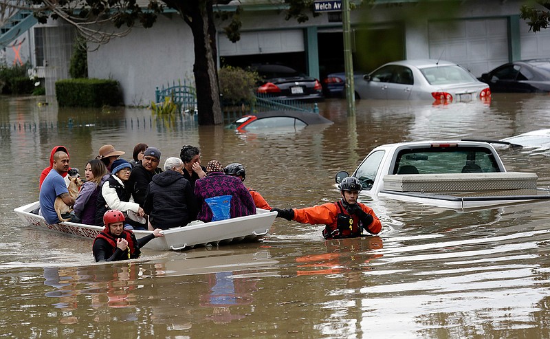 Rescue crews take out residents from a flooded neighborhood Tuesday, Feb. 21, 2017, in San Jose, Calif. Rescuers chest-deep in water steered boats carrying dozens of people, some with babies and pets, from a San Jose neighborhood inundated by water from an overflowing creek Tuesday. 