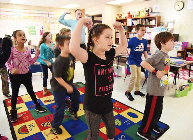 Lily Ahnert, foreground left, and Gavin Dixon, along with fellow third-graders at Callaway Hills Elementary School, follow along with a video as they mimic exercise moves and sing. Using GoNoodle Plus, they sang and answered math questions, all while exercising to music and follow-along steps and movements shown on the smartboard.