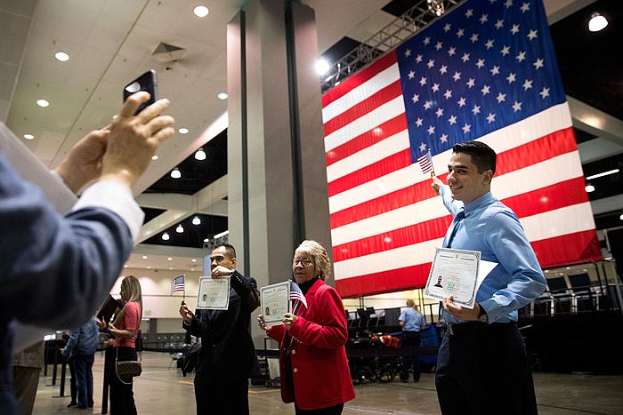 Erik Danialian, a 21-year-old immigrant from Iran, poses last week with his U.S citizenship certificate in front of a large U.S. flag after a naturalization ceremony at the Los Angeles Convention Center.
