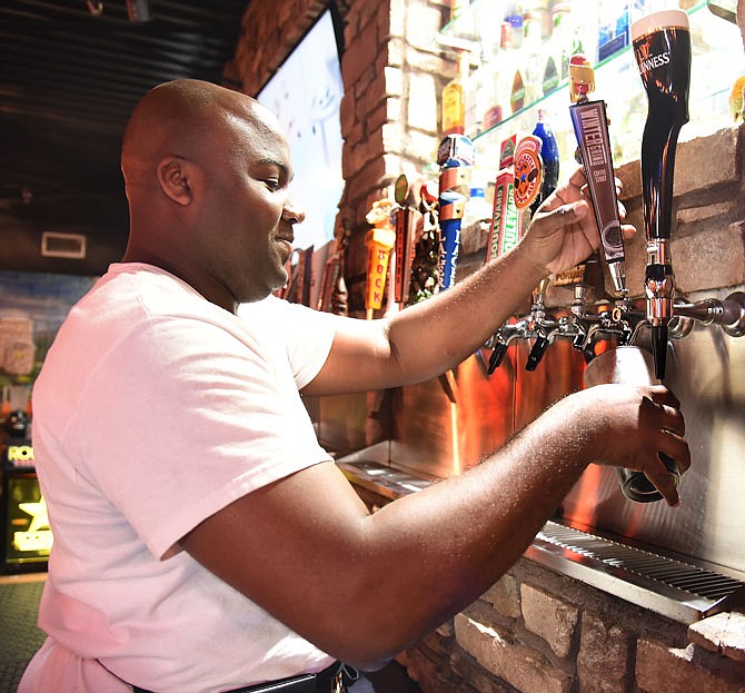 Anthony Brown, a server at Hoxton Tavern, draws a coffee stout draught beer for a customer.
