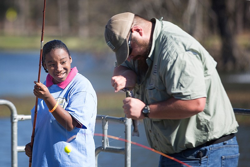 Derronica Talton, a seventh-grader at Atlanta Middle School, watches as Josh DeWyse takes a trout off her line Thursday during the annual Fish Derby at Spring Lake Park in Texarkana, Texas. Area students and adults enjoyed a day of fishing, games and food. This is the 25th year the Texarkana parks department has hosted the two-day event.