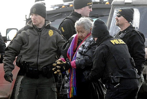An elderly woman is escorted to a transport van after being arrested by law enforcement at the Oceti Sakowin camp as part of the final sweep of the Dakota Access pipeline protesters in Morton County, Thursday, Feb. 23, 2017, near Cannon Ball, N.D. (Mike McCleary/The Bismarck Tribune via AP, Pool)