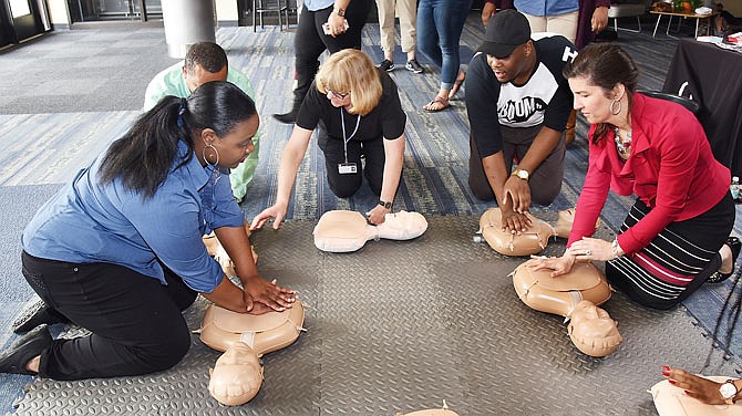 Shakera Garrard, left, a program coordinator at the Women's Resource Center at Lincoln University, shows a group including Mayor Carrie Tergin, at right, and LU student Jonathon Jackson, second from right, the proper chest compression technique Thursday during a hands-only CPR training event. In the middle is Carol Pettigrew, a registered nurse from Capital Region Medical Center, who's working with Carlos Graham, second from left. 