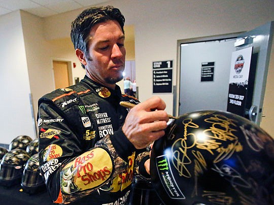 Martin Truex Jr. autographs helmets for race sponsor Monster Energy drink during the Daytona 500 media day Wednesday at Daytona International Speedway in Daytona Beach, Fla.