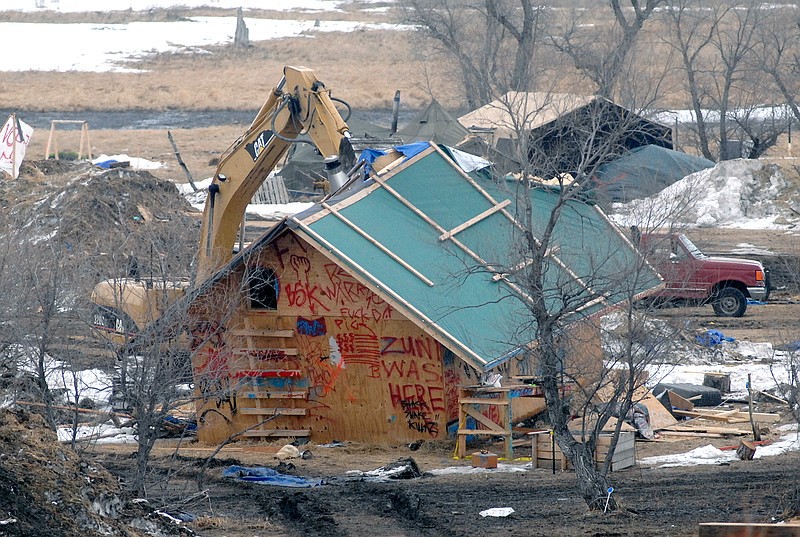 A backhoe rips through a wood structure to begin the cleaning up process at the Oceti Sakowin camp as law enforcement swept through the camp arresting the final Dakota Access oil pipeline protesters in Morton County Thursday, Feb. 23, 2017, near Cannon Ball, N.D.