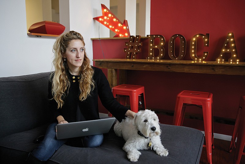 In this photo taken Tuesday, Feb. 21, 2017, Ashley Breinlinger, a senior vice president at BOCA Communications, poses with her dog Bella at her offices in San Francisco. Breinlinger describes this flu season as the ugliest she's seen in 10 years, in terms of how sick people are getting. 