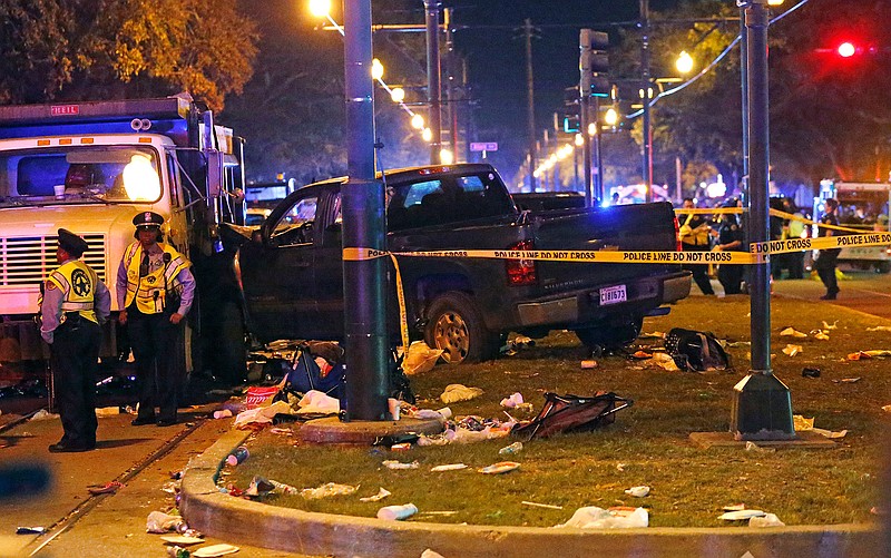 Police stand next to a pickup truck that slammed into a crowd and other vehicles, causing multiple injuries, coming to a stop against a dump truck, during the Krewe of Endymion parade in New Orleans, Saturday, Feb. 25, 2017.