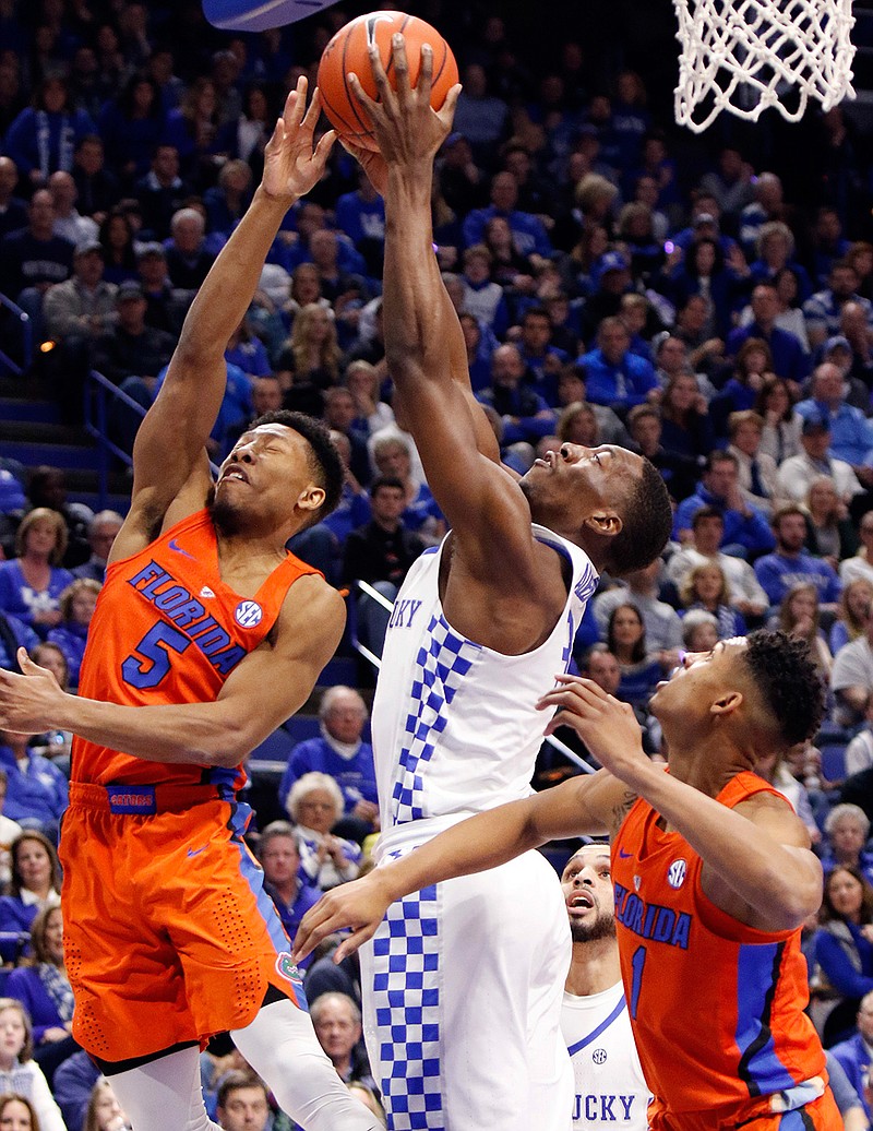 Kentucky's Edrice "Bam" Adebayo, center, pulls down a rebound between Florida's KeVaughn Allen, left, and Devin Robinson, right, during the first half of an NCAA college basketball game, Saturday, Feb. 25, 2017, in Lexington, Ky. 