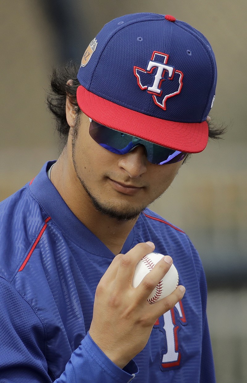 Texas Rangers pitcher Yu Darvish looks at a ball during spring training baseball practice, Wednesday, Feb. 22, 2017, in Surprise, Ariz. 