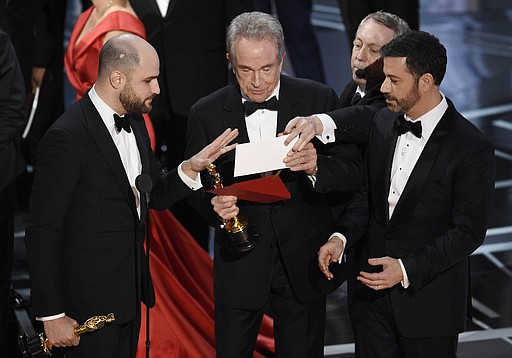 "La La Land" producer Jordan Horowitz, left, presenter Warren Beatty, center, and host Jimmy Kimmel right, look at an envelope announcing "Moonlight" as best picture at the Oscars on Sunday, Feb. 26, 2017, at the Dolby Theatre in Los Angeles. It was originally announced mistakenly that "La La Land" was the winner. 