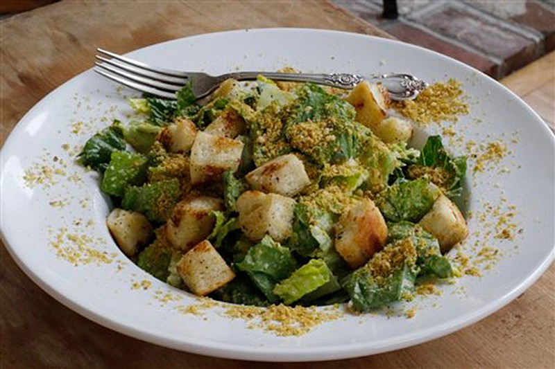 This March 28, 2016 photo shows a vegan Caesar salad. "Undressing" your food by sparingly adding extras like salad dressings, sauces and condiments can limit calories and salt content. (AP Photo/J.M. Hirsch)