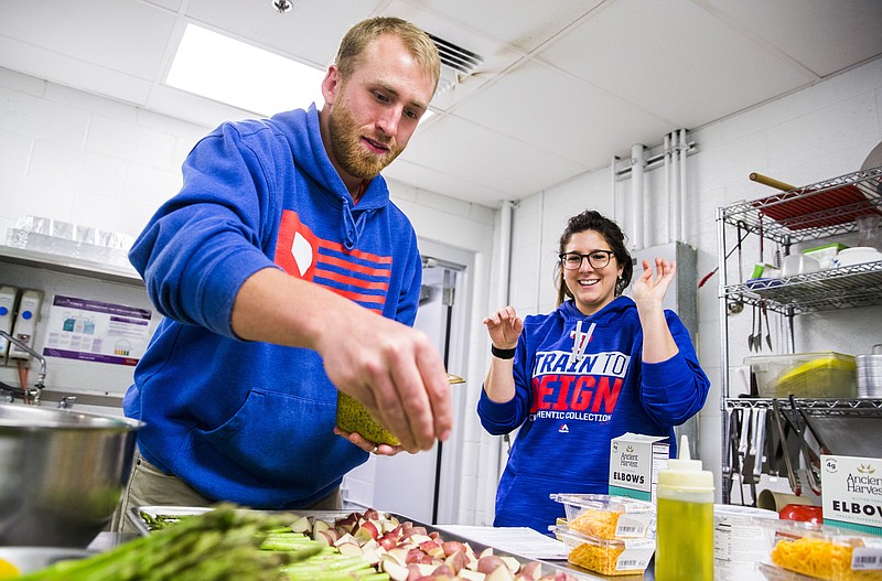 Texas Rangers nutritionist Stephanie Fernandes, right, tells minor league pitcher Reed Garrett to season a tray of vegetables during a spring training cooking class at the team's training facility on Thursday, Feb. 23, 2017 in Surprise, Ariz. 