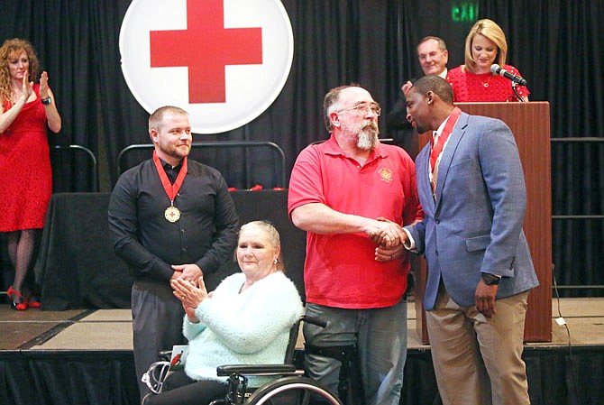 Bob Maxwell, center, and Pam Maxwell thank Jacob Ellis, right, and Adam Brunk for rescuing them in an August car wreck during Wednesday's Red Cross Heart of Heroes dinner at the Capitol Plaza Hotel.  