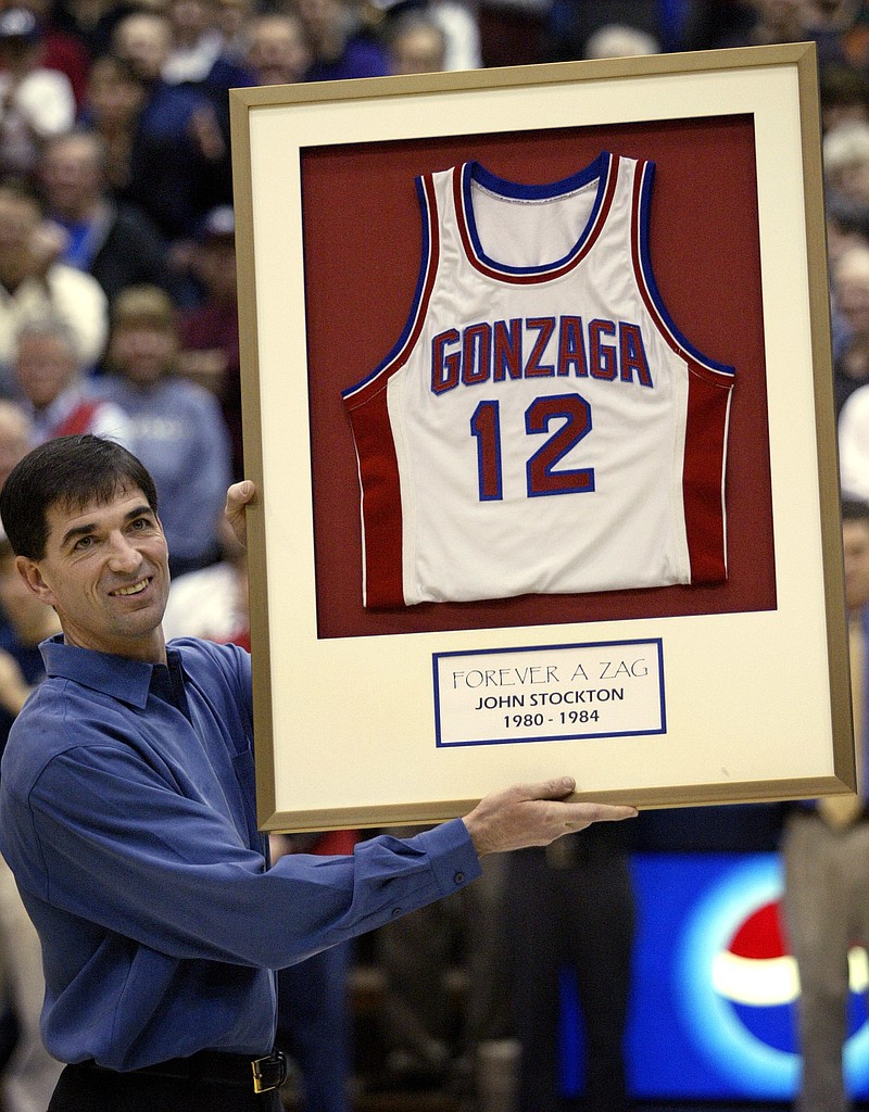 In this Feb. 18, 2004, file photo, John Stockton holds up a replica of his former No. 12 Gonzaga jersey before his number was offically retired during halftime ceremonies of the Portland at Gonzaga NCAA college basketball game, in Spokane, Wash. Wake Forest star Tim Duncan, Gonzaga's John Stockton and Duke standout Jay Williams headline the seven-member class that will be inducted into the National Collegiate Basketball Hall of Fame later this year. The 12th induction class was announced Wednesday, March 8, 2017. 