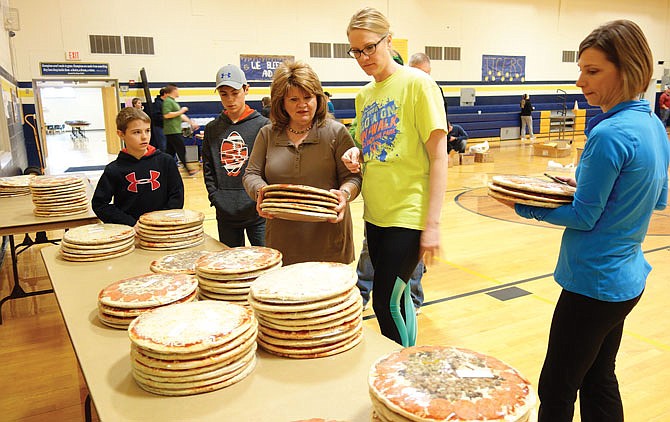 Jaclyn Thessen, in the yellow shirt, works with volunteers at St. Francis Xavier School to distribute pizzas for the school's annual spring fundraiser. To her left is Brenda Christy, who helps coordinate the sale with B.C. & Company, and Sheila Hair is on the right. Thessen hoped the fundraiser would bring in $14,000, which will go to the church.