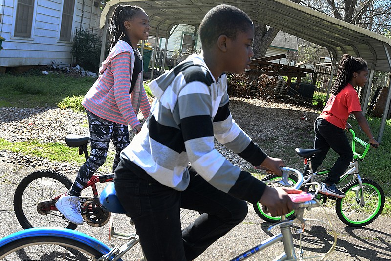 Alexis Hendrix, left, Tayshaun Riles, center, and Treshaun Riles bike down Elizabeth Street on Monday afternoon after the skies cleared up.  