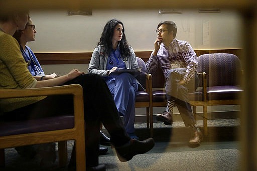In this Monday, Feb. 27, 2017, photo, Cambridge Hospital first-year residents Samantha Harrington, center, and Vikas Gampa, right, talk during "sign-out" at the hospital in Cambridge, Mass. That's when the rookie doctors exchange information about their patients during shift change. Effective this summer, rookie doctors can work up to 24 hours straight under new extended limits. A Chicago-based group that establishes work standards for U.S. medical school graduates has eliminated a 16-hour cap for first-year residents. 