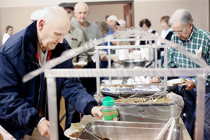 Robert Rephlo, left, serves himself food Friday at the St. Andrew's Catholic Church fish fry in Holt Summit. The fish fry was busy this week despite a "Paddy Pardon" by the diocese that gave some Catholics permission to eat St. Patrick's Day corned beef on a day they are normally supposed to abstain from eating meat. 