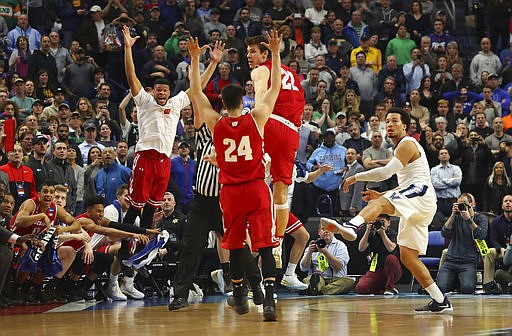 Villanova guard Jalen Brunson (1) follows through on a final shot as Wisconsin players celebrate the end of their second-round men's college basketball game in the NCAA Tournament, Saturday, March 18, 2017, in Buffalo, N.Y. 