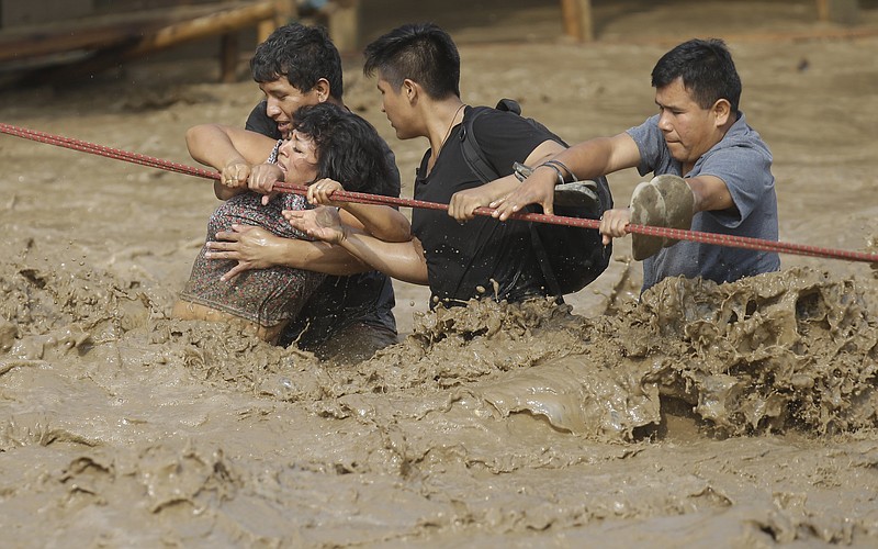 A group of people, stranded in flood waters, hold onto a rope as they wade through flood waters to safety in Lima, Peru, Friday, March 17, 2017. Intense rains and mudslides over the past three days have wrought havoc around the Andean nation and caught residents in Lima, a desert city of 10 million where it almost never rains, by surprise. 