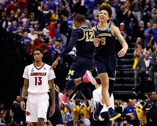 Michigan teammates Muhammad-Ali Abdur-Rahkman (12) and D.J. Wilson (5) celebrate as Louisville's Ray Spalding (13) walks past Sunday following a second-round game in the NCAA Tournament in Indianapolis. Michigan won 73-69.
