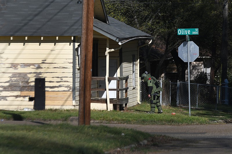 A member of the Plano, Texas, Police Department Bomb Squad inspects a grenade that was found Tuesday underneath the porch of the home on the corner of 39th and Olive Streets in Texarkana, Texas. Texas-side police and firefighters blocked off the area and evacuated homes within two blocks of the house where the grenade was found until it could be safely detonated.