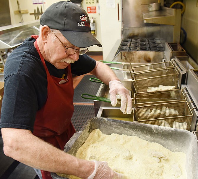  Ted Sigite covers seasoned catfish strips in breading before dropping them into the hot oil March 17 at the American Legion. A crew there is preparing fish for lunch on Fridays during Lent. 
